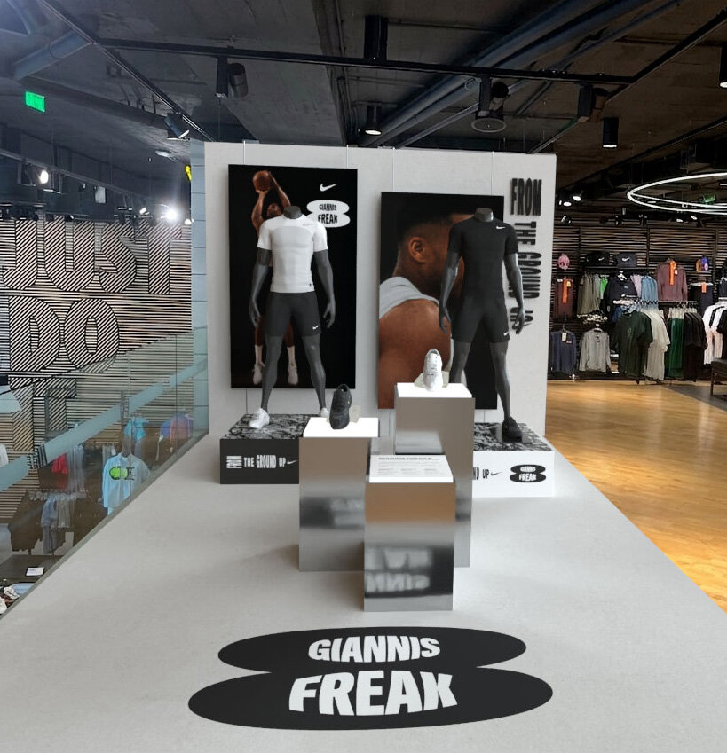 Nike Ermou FA26 Giannis Freak 8 install: looking back along the floor mark toward the apparel wall.